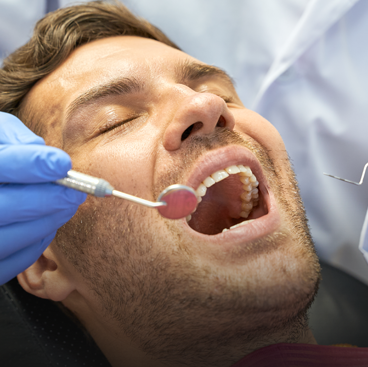 dentist examining patient teeth with mouth mirror